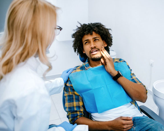 Male patient receiving dental examination from female dentist in clinical office setting.